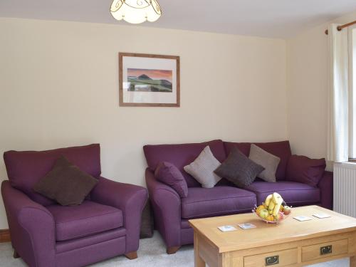 a living room with purple couches and a coffee table at Woodpecker Rest in Cilgerran