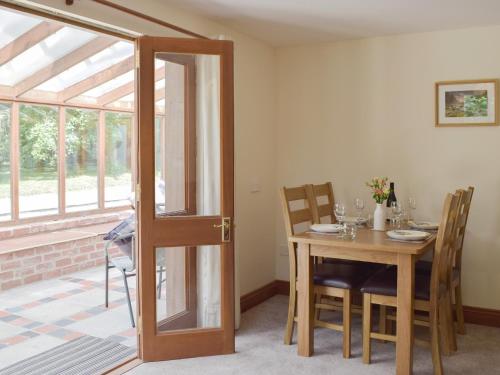 a dining room with a table and a glass door at Woodpecker Rest in Cilgerran