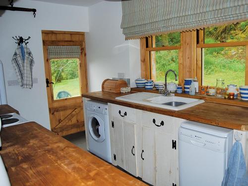 a kitchen with a sink and a washing machine at Shore Cottage - S4600 in Tarbert