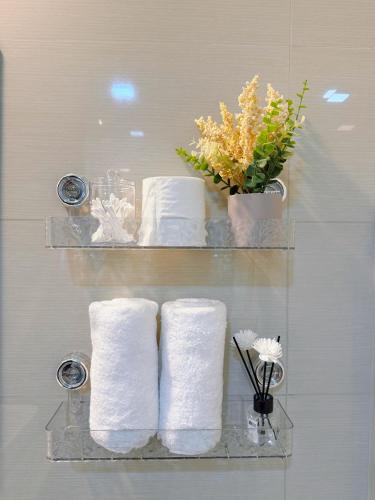 a shelf with three towels and a vase with flowers at Parksuites Tower 2 in Manila