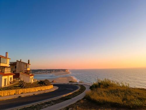 a winding road next to the ocean at sunset at Foz do Arelho Sunset Sea Views Apartment in Foz do Arelho