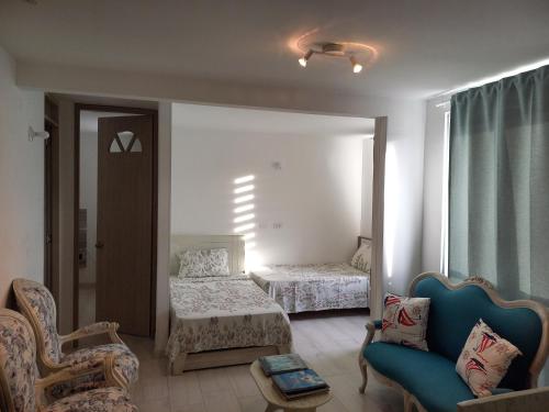 a room with two beds and a couch and a chair at Reserva del Peñón Girardot - Apartamento Vacacional Familiar Confort La Esmeralda in Girardot