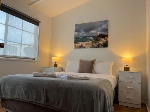 a bedroom with a bed with two lamps and a window at Robe Nampara Cottages in Robe