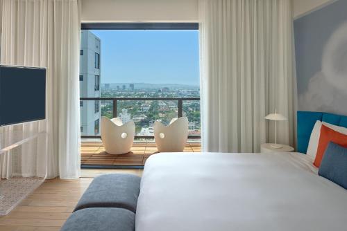 ein Schlafzimmer mit einem großen Bett und einem großen Fenster in der Unterkunft The Valorian Los Angeles, Curio Collection by Hilton in Los Angeles