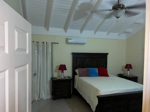 a bedroom with a bed with two lamps and a ceiling at Serenity Vacation Villa in Ocho Rios