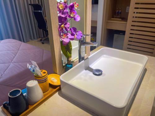 a bathroom sink with a mirror and a vase of flowers at Villas 930 Oceanami in Long Hai
