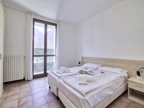 a white bedroom with a large bed and a window at Mobilehome am Luganersee in Porlezza