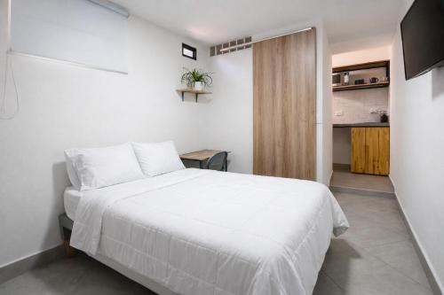 a bedroom with a white bed and a kitchen at Casa hotel Los Laureles in Medellín