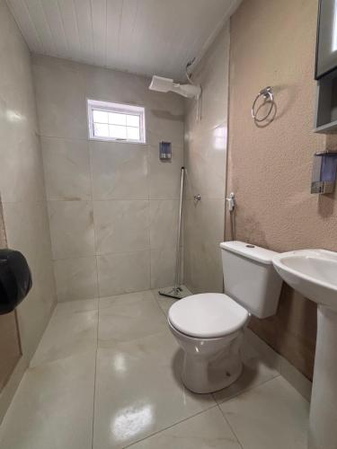 a white bathroom with a toilet and a sink at Pousada Bem-Te-Vi in Rondonópolis