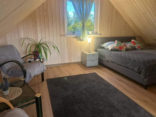 a bedroom with a bed and a chair and a window at Comfortable holiday home, pool, sauna, jacuzzi in Brzuze