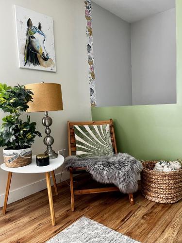ein Zimmer mit einem Stuhl, einem Tisch und einem Pferdebild in der Unterkunft Modern Maple Flat in Maple Ridge District Municipality