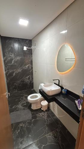 a bathroom with a sink and a toilet and a mirror at Vista Bela Guesthouse in Barra do Garças