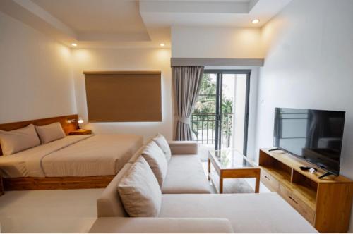 a bedroom with a bed and a tv and a couch at La Cha Cha Residence in Ban Thalat Choeng Thale