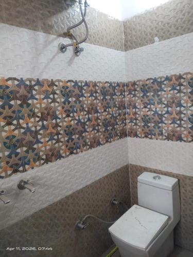 a bathroom with a toilet and a tiled wall at Guest house one room 9&&&&So&&2 in Kharar