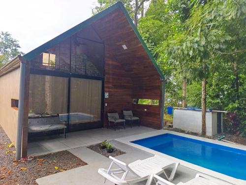 a small house with a swimming pool in the backyard at Cabaña Kono Rainbow Finca paraíso in Jiménez