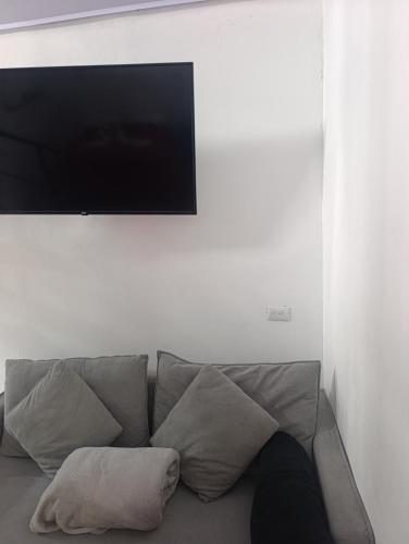 a person sitting on a couch under a flat screen tv at Cabaña Kono Rainbow Finca paraíso in Jiménez