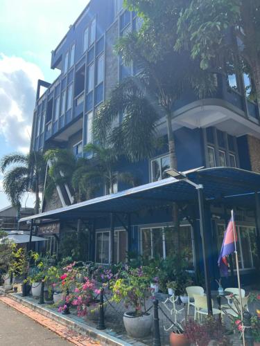 a blue building with plants and flowers in front of it at Ocean Breeze Hotel in Kep