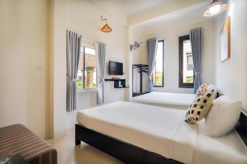 a white bedroom with a bed and two windows at Y's La House in Hoi An