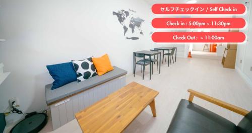a room with a bench and a table and chairs at TRANSIT HOSTEL Cafe and Bar in Izumi-Sano