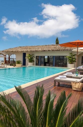a resort with a swimming pool with chairs and an umbrella at Baan Jai Dee Beach Front Hotel in Wok Tum