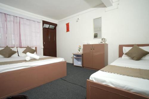 a hotel room with two beds and a bathroom at Himavati Retreat in Darjeeling
