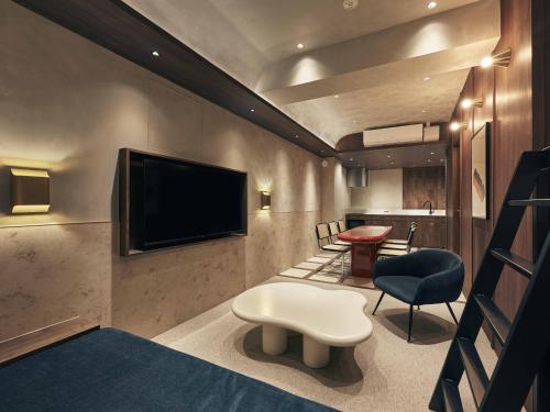 a room with a tv and a chair and a stool at illi Noa Hamamatsucho in Tokyo