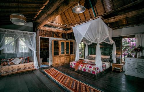 a bedroom with a bed with curtains and a rug at Batukaru Coffee Estate in Tabanan