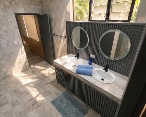 a bathroom with two sinks and two mirrors at CulturaHumana Guesthouse in Panama City