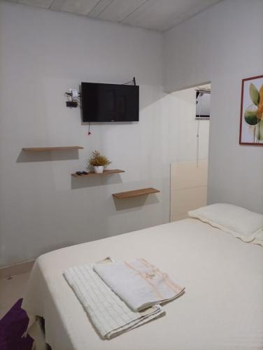 a white bedroom with a bed with a tv on the wall at Recanto da Serra Vazante in Vazante