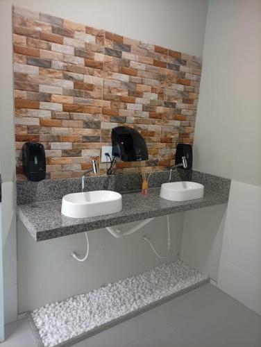 a bathroom with two sinks and a brick wall at Recanto da Serra Vazante in Vazante