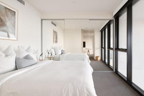 a bedroom with two white beds and large windows at The Calm in Newcastle