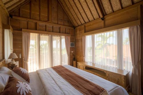 a bedroom with a bed and a large window at Jero Jawi Javanese Villa in Lebih