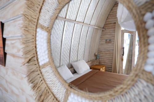 a mirror reflection of a bed in a room at Jungle Gili Air in Gili Islands