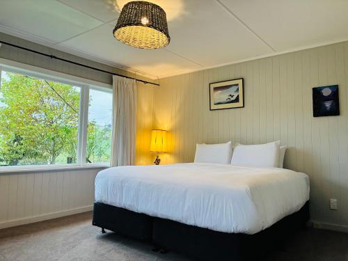 a bedroom with a large white bed and a window at The Black Barn At Puketitiri in Puketitiri