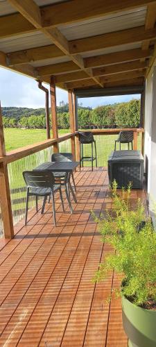 a patio with a table and benches on a deck at Bream Bay Views in Ruakaka