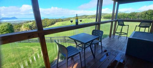 a balcony with chairs and a table and a view at Bream Bay Views in Ruakaka