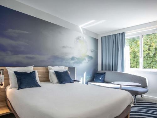 a bedroom with a large bed and a couch at Novotel Valence Sud in Valence