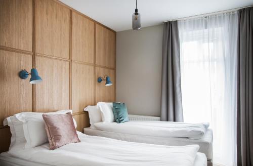 two beds in a hotel room with a window at Ódinsvé Hotel Apartments in Reykjavík