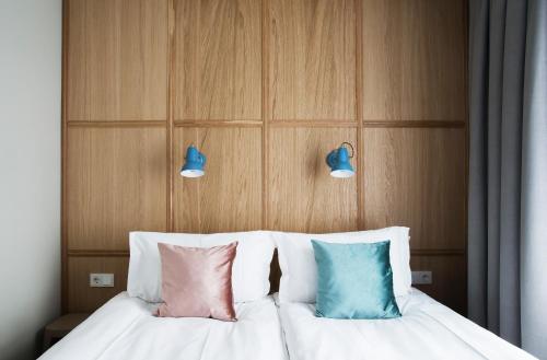 a bed with three pillows and two lights above it at Ódinsvé Hotel Apartments in Reykjavík