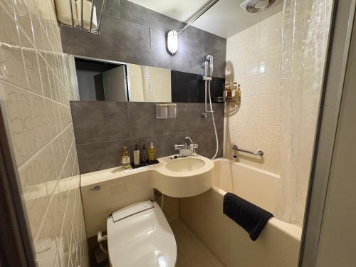 a bathroom with a sink and a toilet and a tub at Peace INN Masuda-ekikita in Masuda