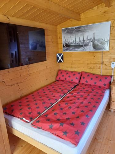 a bed in a cabin with a red comforter at Chalet Glamping in Myza Igaste