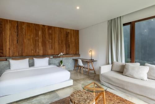 a bedroom with a white bed and a couch at Aria Villas Ubud in Ubud