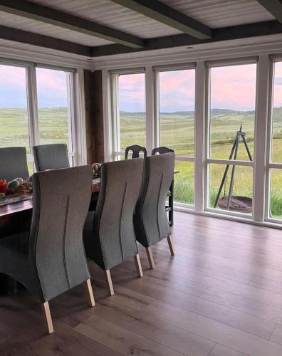 a dining room with a table and chairs and windows at Renovated Mountain Cabin With Mountain Views in Al