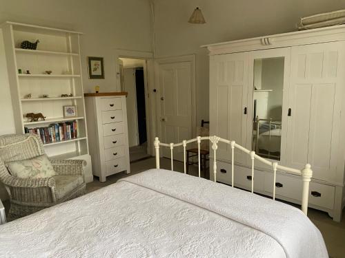 a bedroom with a white bed and a chair at Mount Charles Homestead in Charleston