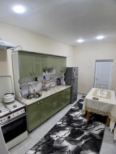 a kitchen with green cabinets and a sink and a table at Uyut house in Samarkand