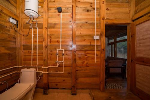 a bathroom with wooden walls and a toilet and a sink at Forest Rest House Satobari in Dharamshala