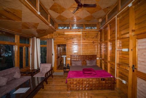 a bedroom with a bed in a room with wooden walls at Forest Rest House Satobari in Dharamshala
