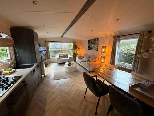 a kitchen and living room with a couch and a table at VELUWSHOF HOENDERLOO HOLIDAYS Luxe Holidayhomes with PRIVATE JACUZZI'S - SwimmingPool - Tennis Court - Bowling - Supermarket and Children Entertainment in Hoenderloo