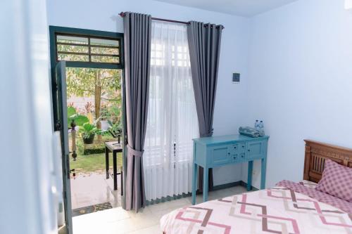 a bedroom with a bed and a desk and a window at Luchis HOME Ijen in Banyuwangi