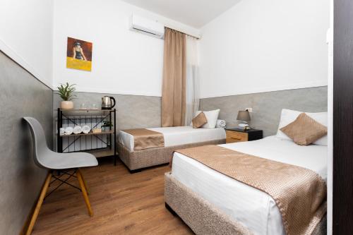 a hotel room with two beds and a chair at Budget Hotel Rooms In Yerevan in Yerevan